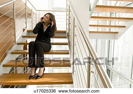 Businesswoman talking on cell phone on office staircase View Large Photo Image Stock Photograph - Businesswoman talking on cell phone on office staircase. Fotosearch