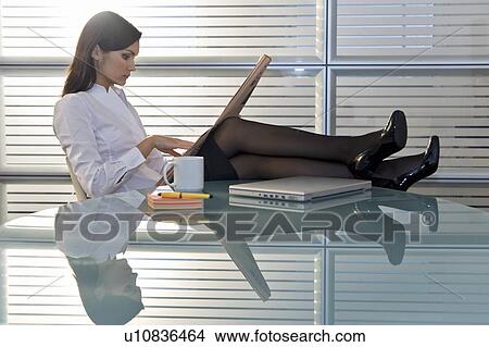 Professional woman reading newspaper with legs up on desk View Large Photo Image Picture - Professional woman reading newspaper with legs up on desk. Fotosearch