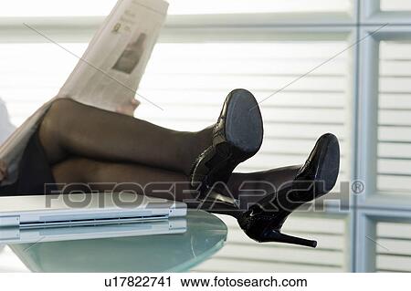 Professional woman reading newspaper with legs up on desk View Large Photo Image Stock Image - Professional woman reading newspaper with legs up on desk. Fotosearch