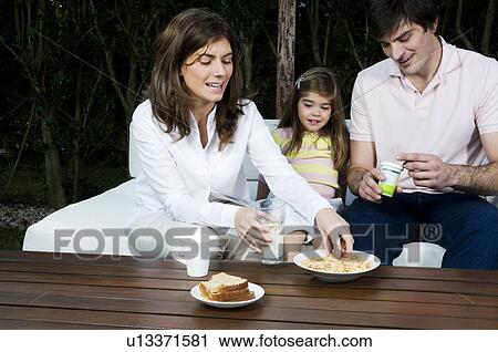 Stock Image - Young couple and girl having breakfast outdoors. Fotosearch