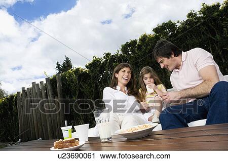 Stock Image - Young couple and girl having breakfast outdoors. Fotosearch