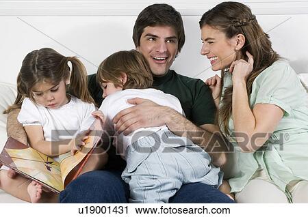 Young couple on couch with children reading View Large Photo Image Stock Image - Young couple on couch with children reading. Fotosearch