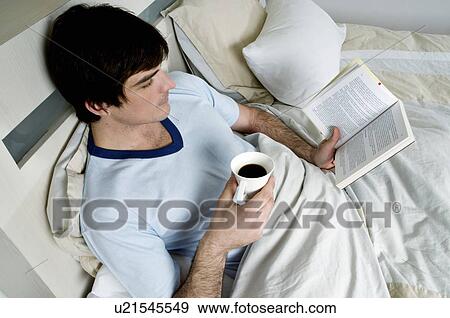 Young man in bed with book and coffee cup View Large Photo Image Stock Photo - Young man in bed with book and coffee cup. Fotosearch