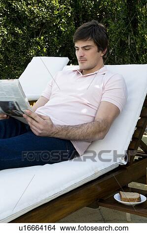 Young man on chaise lounge reading View Large Photo Image Picture - Young man on chaise lounge reading. Fotosearch