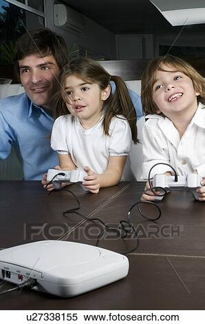 Stock Photography - Young man with children playing video game. Fotosearch