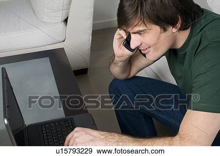 Young man with laptop computer and phone View Large Photo Image Stock Photo - Young man with laptop computer and phone. Fotosearch