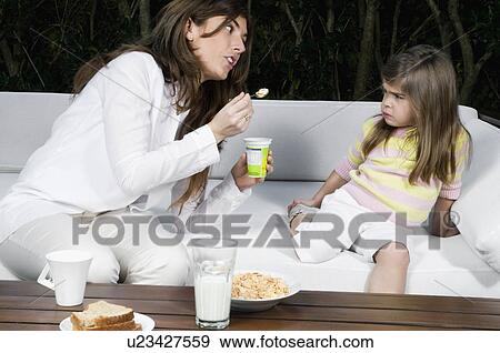 Stock Photo - Young woman and girl having breakfast outdoors. Fotosearch