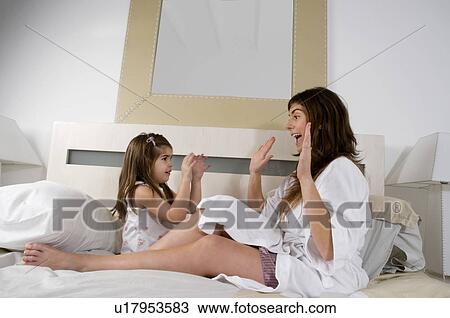 Young woman and girl on bed playing View Large Photo Image Stock Image - Young woman and girl on bed playing. Fotosearch