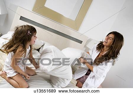 Young woman and girl on bed playing View Large Photo Image Stock Photo - Young woman and girl on bed playing. Fotosearch