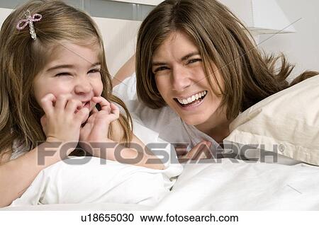 Young woman and girl on bed smiling View Large Photo Image Stock Image - Young woman and girl on bed smiling. Fotosearch