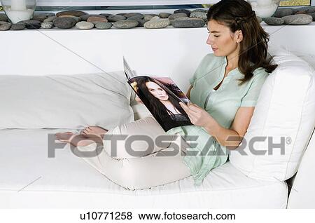 Young woman on couch reading magazine View Large Photo Image Stock Photo - Young woman on couch reading magazine. Fotosearch