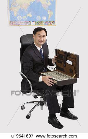 Stock Photo - Businessman holding a suitcase with paper money, Business People. Fotosearch