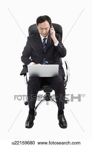 Businessman sitting on chair, using laptop and on the phone, Business People View Large Photo Image Stock Image - Businessman sitting on chair, using laptop and on the phone, Business People. Fotosearch