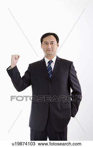 Stock Image - Businessman standing with one fist up, Business People. Fotosearch