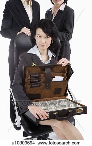 Picture - Businesswoman sitting and holding a suitcase with paper money, Business People. Fotosearch