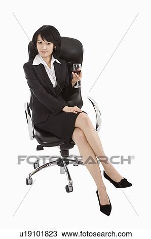 Stock Image - Businesswoman sitting on chair and holding a glass of drink, Business People. Fotosearch