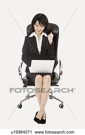 Stock Image - Businesswoman sitting on chair and using laptop, Business People. Fotosearch