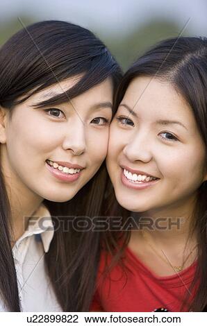 Stock Image - Close-up of two young women smiling happily. Fotosearch