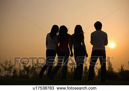 Four people standing in a row and looking at sunset, rear view View Large Photo Image Stock Image - Four people standing in a row and looking at sunset, rear view. Fotosearch