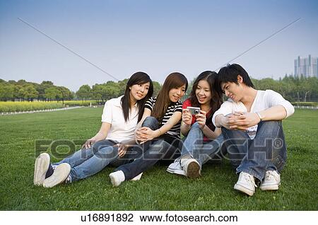 Four young people sitting on the lawn and looking at the camera, Studying, Education View Large Photo Image Stock Image - Four young people sitting on the lawn and looking at the camera, Studying, Education. Fotosearch