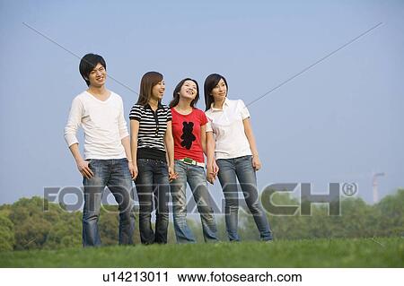 Four young people standing on the lawn and smiling happily View Large Photo Image Stock Image - Four young people standing on the lawn and smiling happily. Fotosearch