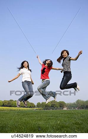 Stock Photo - Three young women jumping high in the mid-air. Fotosearch