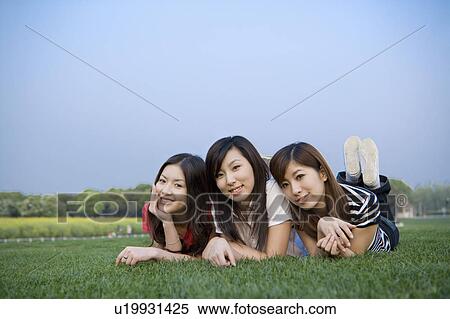 Three young women lying on the lawn and looking at the camera View Large Photo Image Stock Photography - Three young women lying on the lawn and looking at the camera. Fotosearch