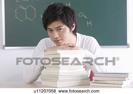 Young man sitting with a stack of books in the classroom, Studying, Education View Large Photo Image Stock Photo - Young man sitting with a stack of books in the classroom, Studying, Education. Fotosearch