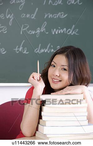 Young woman sitting in the classroom with a stack of books, Studying, Education View Large Photo Image Stock Photograph - Young woman sitting in the classroom with a stack of books, Studying, Education. Fotosearch