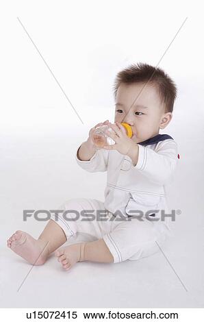 Baby boy holding a baby bottle and sucking, Child View Large Photo Image Stock Photography - Baby boy holding a baby bottle and sucking, Child. Fotosearch