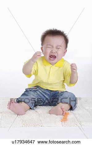 Stock Photo - Baby boy sitting and crying, Child. Fotosearch