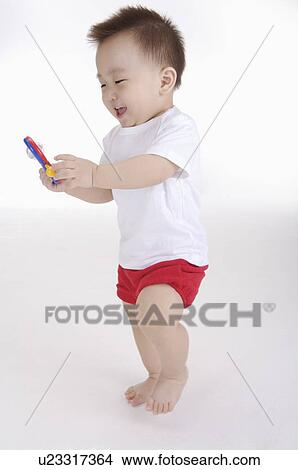 Baby boy standing and playing with a toy, Child View Large Photo Image Picture - Baby boy standing and playing with a toy, Child. Fotosearch