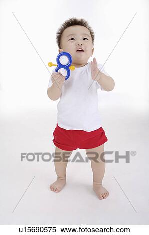 Baby boy standing, holding a toy and looking up, Child View Large Photo Image Stock Photography - Baby boy standing, holding a toy and looking up, Child. Fotosearch