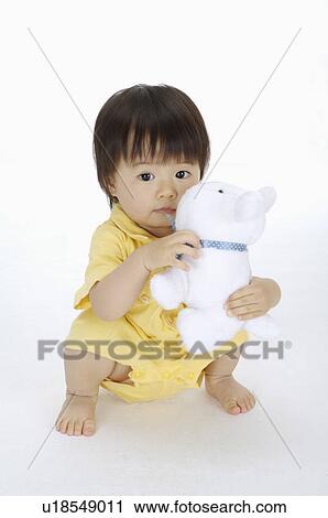 Baby girl crouching and holding a toy, Child View Large Photo Image Stock Image - Baby girl crouching and holding a toy, Child. Fotosearch