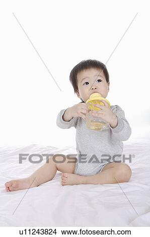 Baby girl holding a baby bottle and sucking, Child View Large Photo Image Picture - Baby girl holding a baby bottle and sucking, Child. Fotosearch