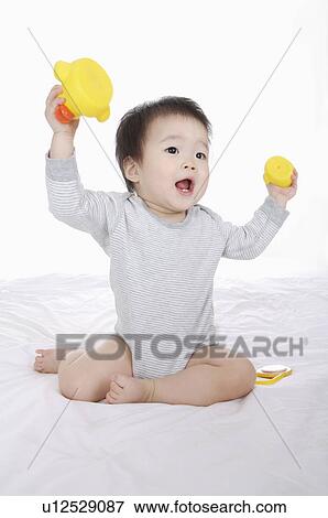 Stock Photo - Baby girl holding rubber duck and playing, Child. Fotosearch