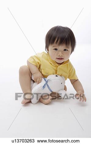 Stock Image - Baby girl playing with toy and looking at the camera, Child. Fotosearch