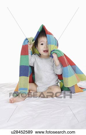 Stock Photo - Baby girl sitting and holding a blanket on head, Child. Fotosearch