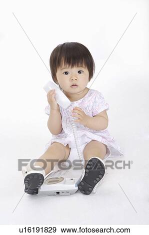 Stock Photo - Baby girl sitting and holding the telephone, Child. Fotosearch