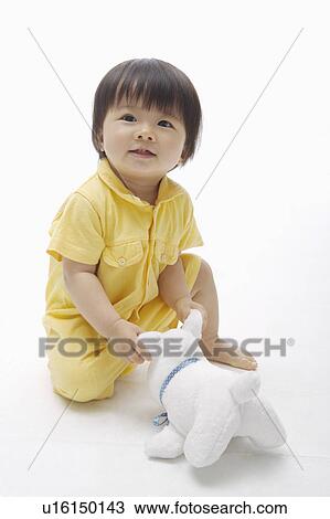 Baby girl sitting with a toy and looking up, Child View Large Photo Image Stock Image - Baby girl sitting with a toy and looking up, Child. Fotosearch