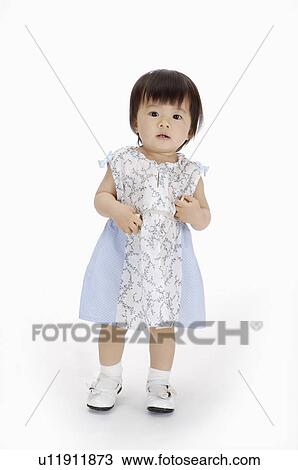 Stock Image - Baby girl standing and looking at the camera, Child. Fotosearch