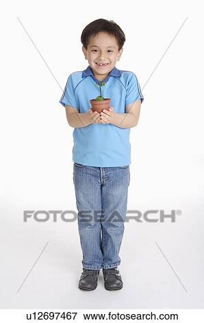 Stock Photo - Boy holding a potted plant and smiling happily, Child. Fotosearch