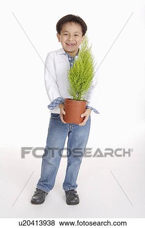 Stock Photo - Boy holding a potted plant and smiling happily, Child. Fotosearch