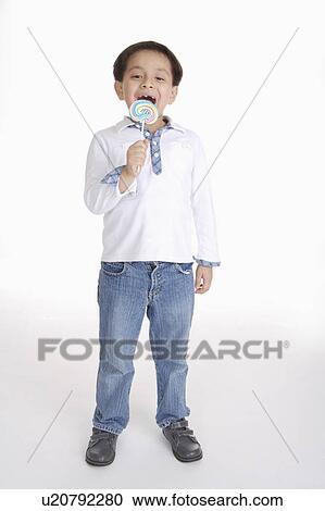 Boy standing and eating a lollipop, Child View Large Photo Image Stock Image - Boy standing and eating a lollipop, Child. Fotosearch