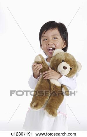 Stock Image - Little girl holding teddy bear and smiling happily, Child. Fotosearch