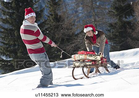 Couple with sleigh and presents in winter scene View Large Photo Image Stock Image - Couple with sleigh and presents in winter scene. Fotosearch