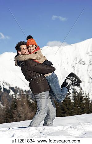 Young man holding young woman up in winter scene View Large Photo Image Picture - Young man holding young woman up in winter scene. Fotosearch