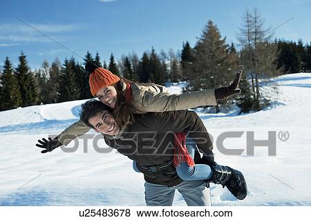 Young woman riding piggyback on young man in winter scene View Large Photo Image Stock Photo - Young woman riding piggyback on young man in winter scene. Fotosearch