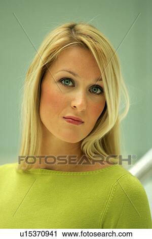 Stock Image - Portrait of young business woman with long blond hair wearing green sweater. Fotosearch