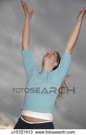 Woman stretching out arms in front of dark clouds, low angle view View Large Photo Image Stock Image - Woman stretching out arms in front of dark clouds, low angle view. Fotosearch